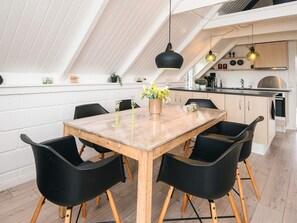 Cozinha moderna com mesa e cadeiras de madeira, luminária pendente e forno embutido.