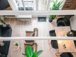 A high-ceilinged lounge area with wicker furniture, a wooden coffee table, and a bench.