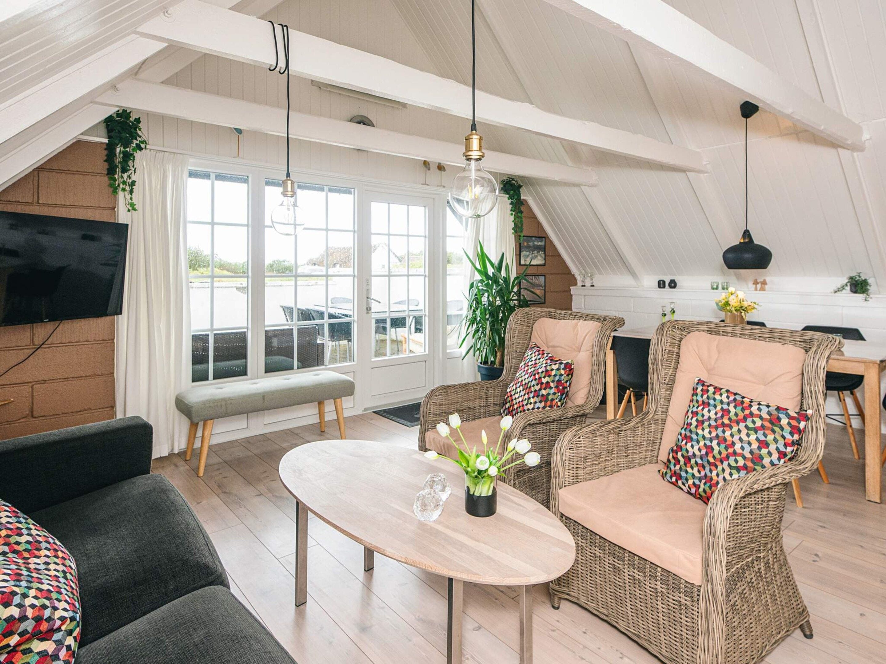A spacious loft with a high ceiling, large windows, and a dining area.
