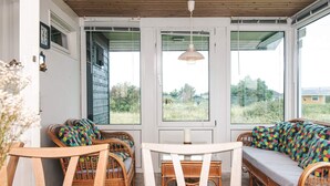 A cozy room with wicker furniture, large windows, and a wooden ceiling. - Cozy Holiday Home in Rømø near Beach (Rømø)