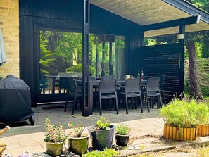 An outdoor patio with a covered seating area, potted plants, and a barbecue grill. - 6 Person Holiday Home in Vaeggerlose-by Traum (Vaeggerlose)