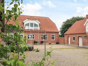 A brick building with a red-tiled roof, a balcony, and a gravel courtyard. - 5 Star Holiday Home in Fur (Fur)