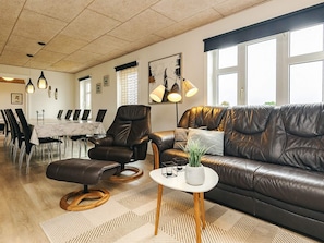A modern living room with a leather sofa, a dining table with chairs, and pendant lighting. - 5 Star Holiday Home in Fur (Fur)