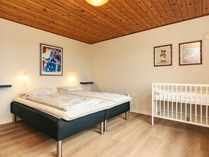 A bedroom with a bed, bedside lamps, a crib, and wall art. - 5 Star Holiday Home in Fur (Fur)