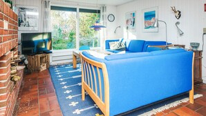 Una sala de estar acogedora con un sofá azul, una mesa de centro de madera y un televisor sobre una pared de ladrillo.