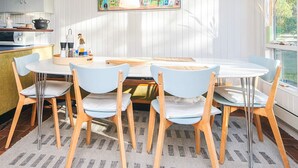 Un comedor con mesa blanca, sillas azules y un cuadro de colores.