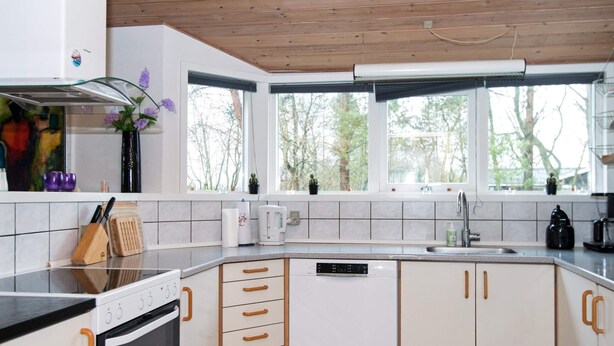 A modern kitchen with white cabinets, a black countertop, and a built-in dishwasher. - 8 Person Holiday Home in Oksbol (Oksbol)