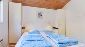 A bedroom with a bed, two bedside tables, a wall-mounted light, a door, and a small painting on the wall. - 8 Person Holiday Home in Oksbol (Oksbol)