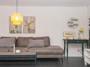 A living room with a sofa, a coffee table, a lamp, and wall art. - 4 Star Holiday Home in Tarm (Tarm)