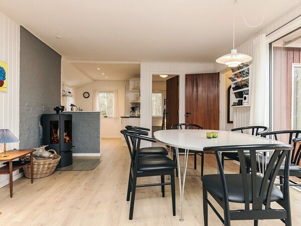 A modern kitchen with a central island, a dining area with a round table and chairs, and a cozy fireplace.