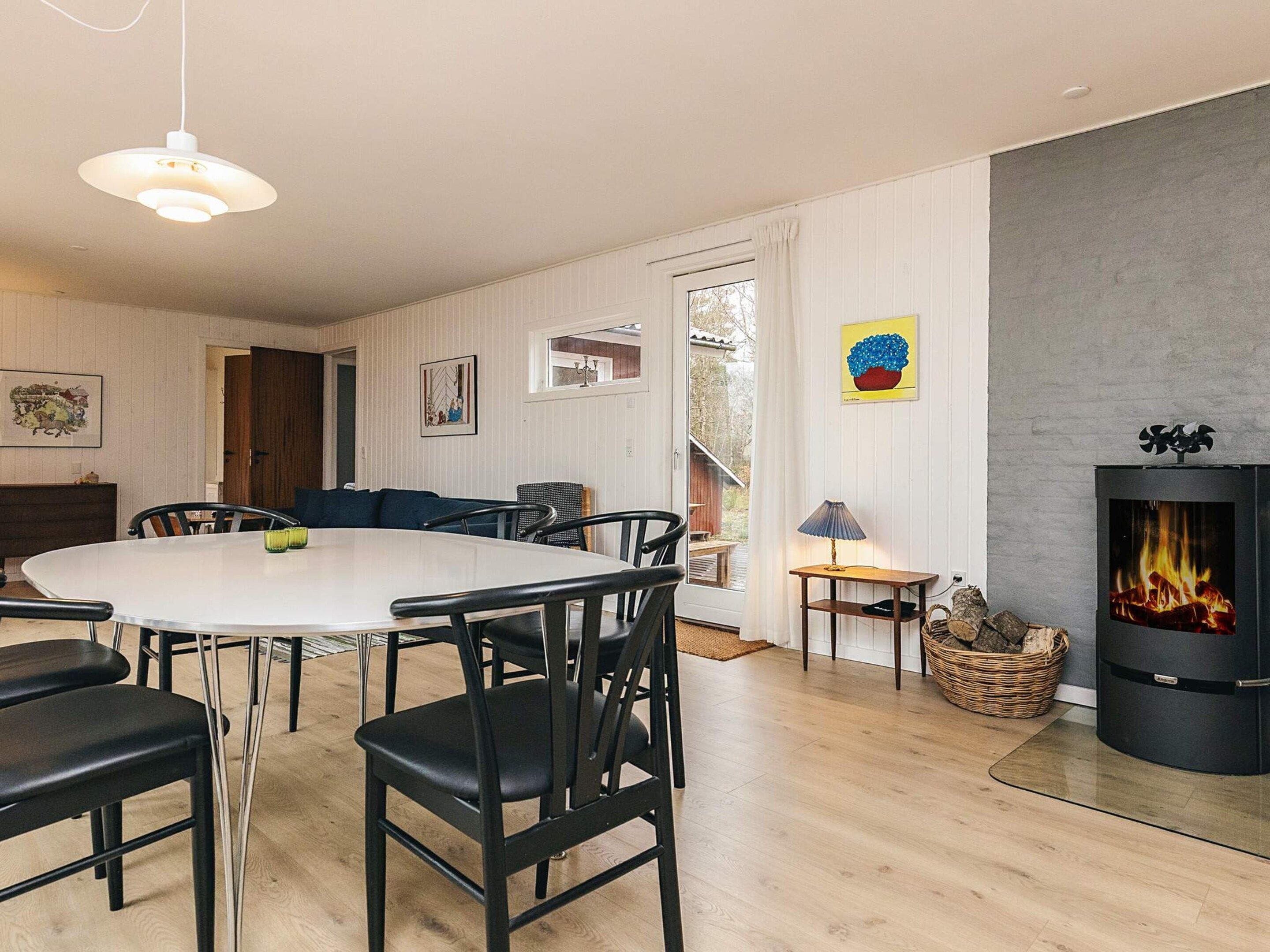 A modern living room with a dining area, a fireplace, and a view of the outdoors.