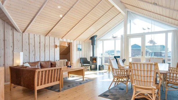 A spacious living area with a wooden ceiling, a sofa, a table, and wicker chairs. - Luxury Retreat With Spa - By Traum Ferienwohnungen (Harboore)
