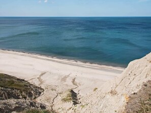 En strand vid kusten med klart, blått vatten och en sandstrand.