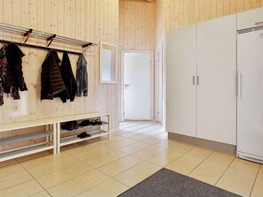A room with a wooden wall, a coat rack with jackets, a white wardrobe, and a shoe shelf. - Spacious Holiday Home in Glesborg near Ocean (Glesborg)