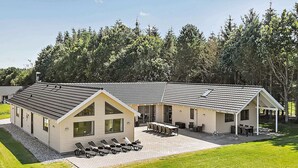 A two-story building with a patio area, a covered seating area, and a large window. - Spacious Holiday Home in Glesborg near Ocean (Glesborg)