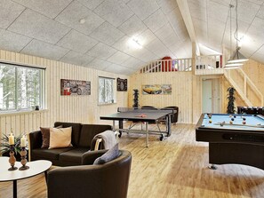 A cozy room with a pool table, a sofa, and a ping pong table.
