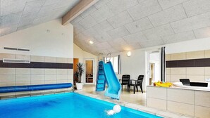 An indoor swimming pool with a blue slide, a reception area, and a seating area with chairs. - Spacious Holiday Home in Glesborg near Ocean (Glesborg)