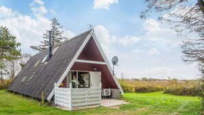 A small, triangular-roofed cabin with a white exterior, a satellite dish, and a visible interior with a bench and a table. - 4 Person Holiday Home in Romo (Rømø)
