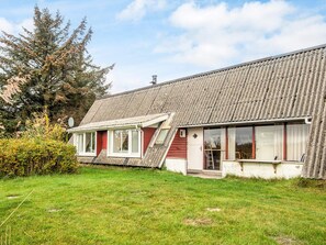 A two-story house with a sloped roof, a small porch, and a grassy yard. - 4 Person Holiday Home in Romo (Rømø)