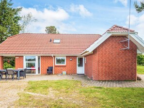 A single-story brick house with a red-tiled roof, a small attached garage, and a patio area with outdoor furniture. - 8 Person Holiday Home in Tarm (Tarm)