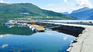 A marina with boats docked, a concrete pier, and a backdrop of green hills and mountains. - Holiday Home in Eidsvåg (Molde)