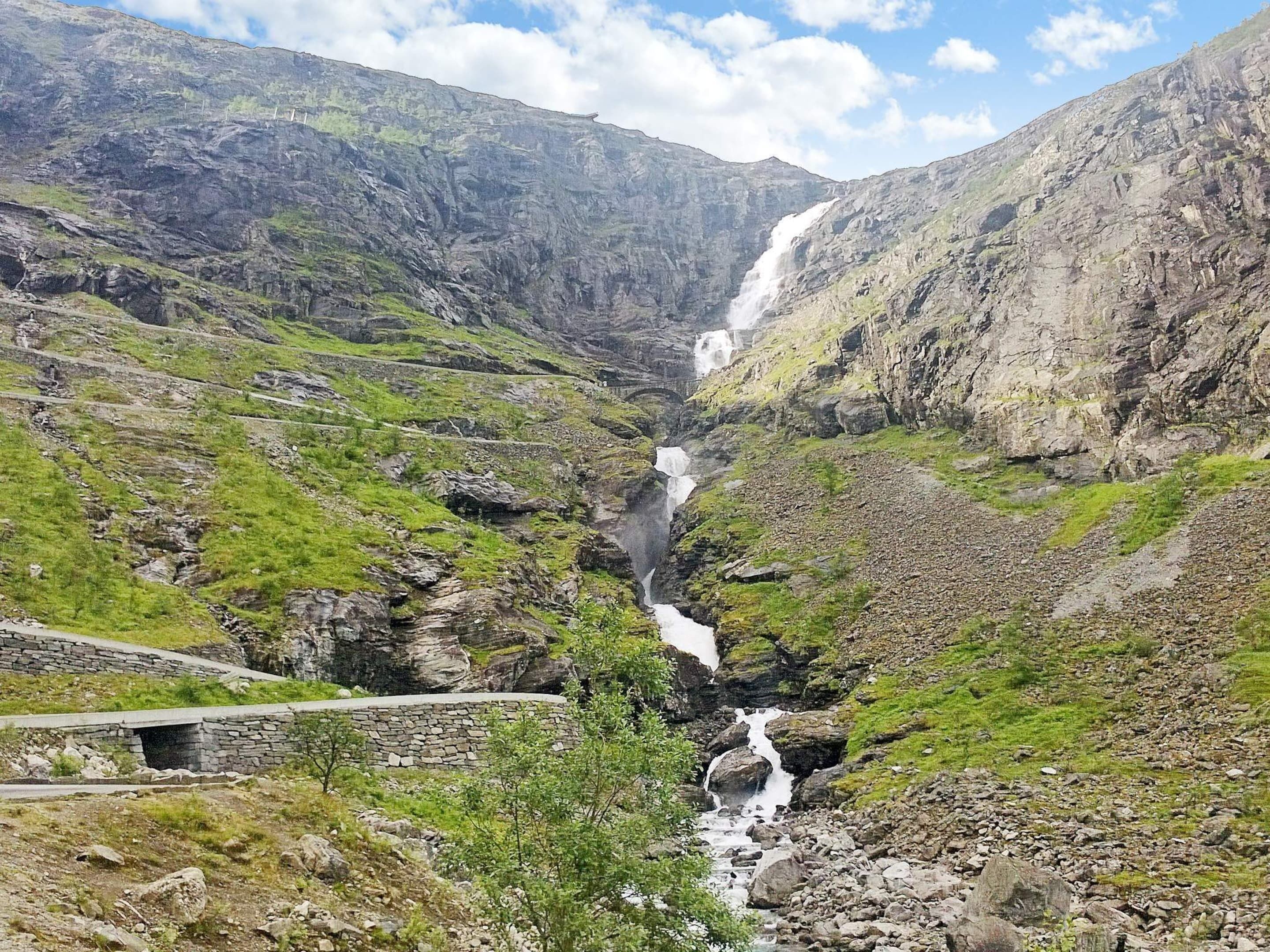 Un paisaje montañoso con una cascada que desciende por un profundo desfiladero rocoso.