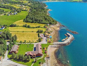 An aerial view of a coastal property with a large house, a swimming pool, and a dock.
