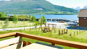 A wooden deck with picnic tables overlooking a lake and mountains.