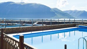 A pool with a stone border and a view of mountains and water.