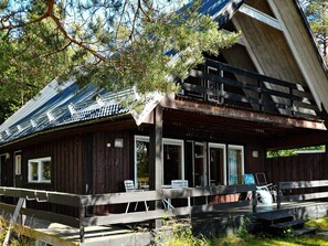 A wooden cabin with a balcony, large windows, and a covered porch area. - 5 Person Holiday Home in Logdea (Lögdeå)
