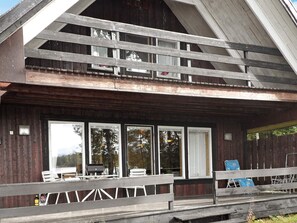 A wooden cabin with a balcony, large windows, and outdoor seating. - 5 Person Holiday Home in Logdea (Lögdeå)