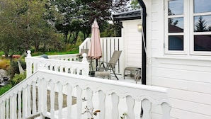 A white deck with a white picket fence, outdoor furniture, and a view of a house with large windows. - Holiday Home in Austrheim (Austrheim)