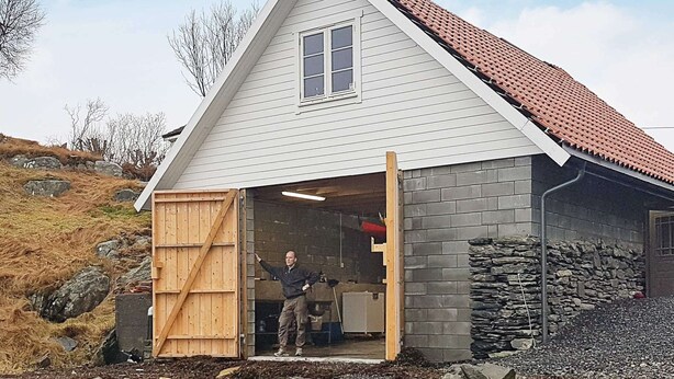 A house with a sloped roof, a wooden door, and a stone wall. - Holiday Home in Austrheim (Austrheim)