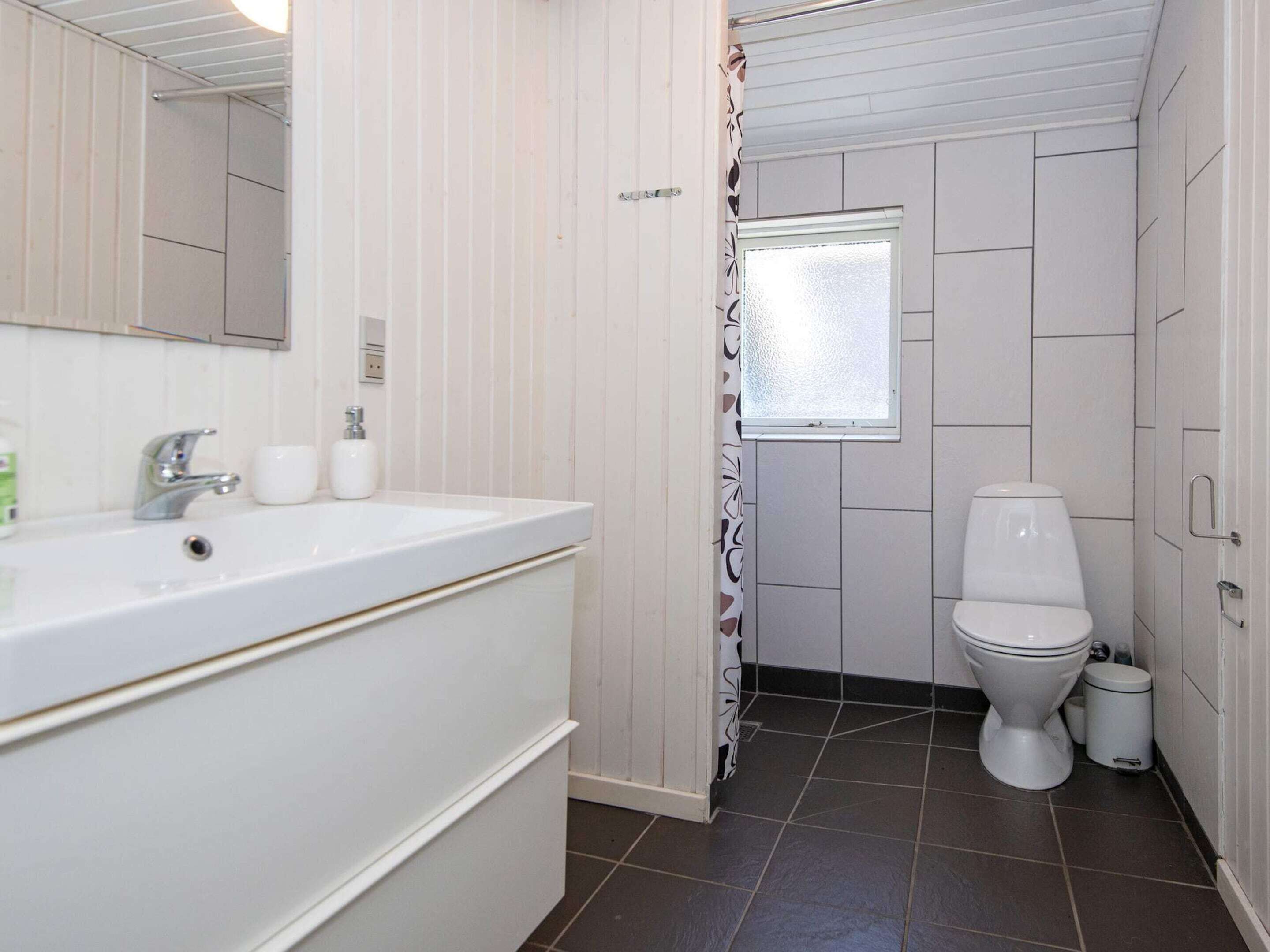 A bathroom with a white sink, mirror, and toilet.