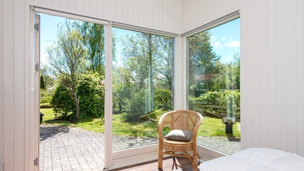 Ein Schlafzimmer mit einer großen Schiebeglastür, die zu einem Garten führt.