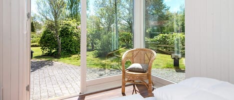 A bedroom with a large sliding glass door leading to a garden.