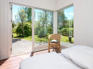 A bedroom with a large sliding glass door leading to a garden. - Cozy Holiday Home in Ørsted near Beach (Ørsted)