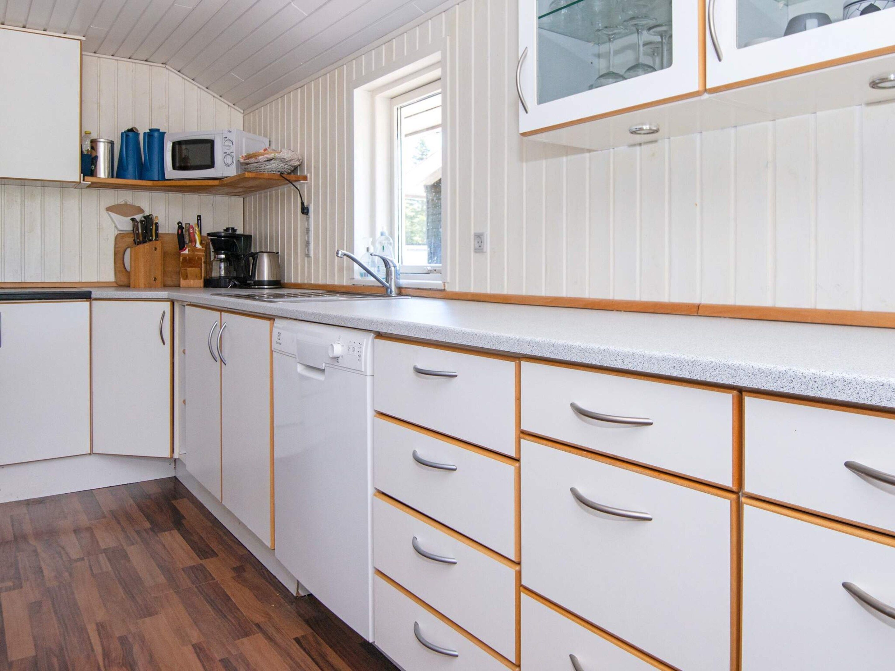 A kitchen with white cabinetry, a wooden countertop, and a dishwasher.