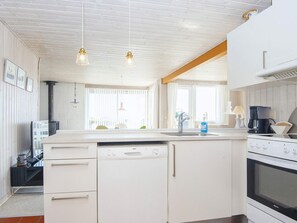 A kitchen with white cabinetry, a dishwasher, an oven, and pendant lighting. - 6 Person Holiday Home in Juelsminde (Horsens)