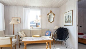 A cozy room with a wooden ceiling, a sofa, a chair, a table, and a mirror. - 6 Person Holiday Home in Juelsminde (Horsens)