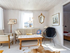 Una habitación acogedora con techo de madera, un sofá, una silla, una mesa y un espejo.