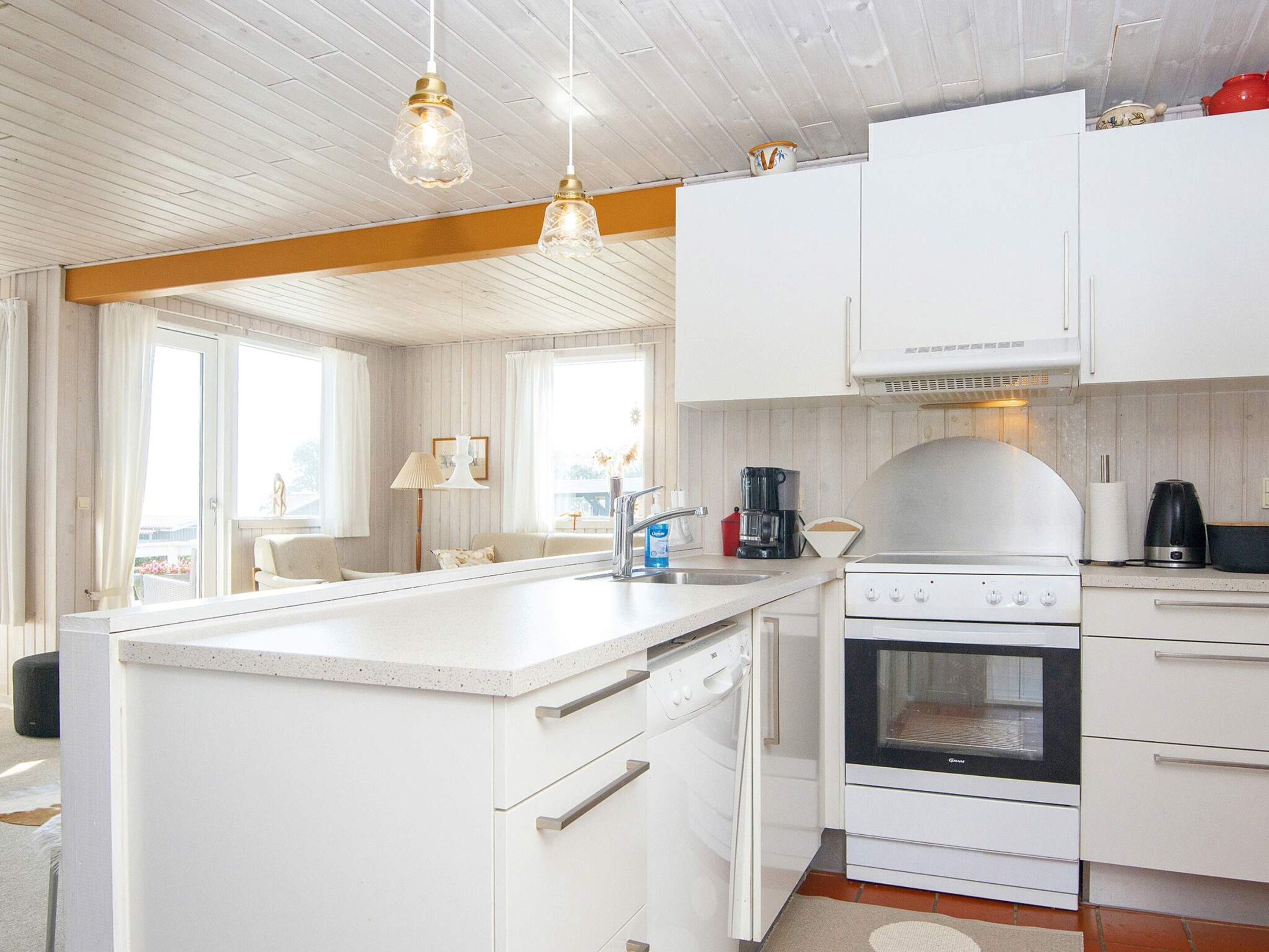 A modern kitchen with white cabinetry, a built-in oven, and a coffee maker.
