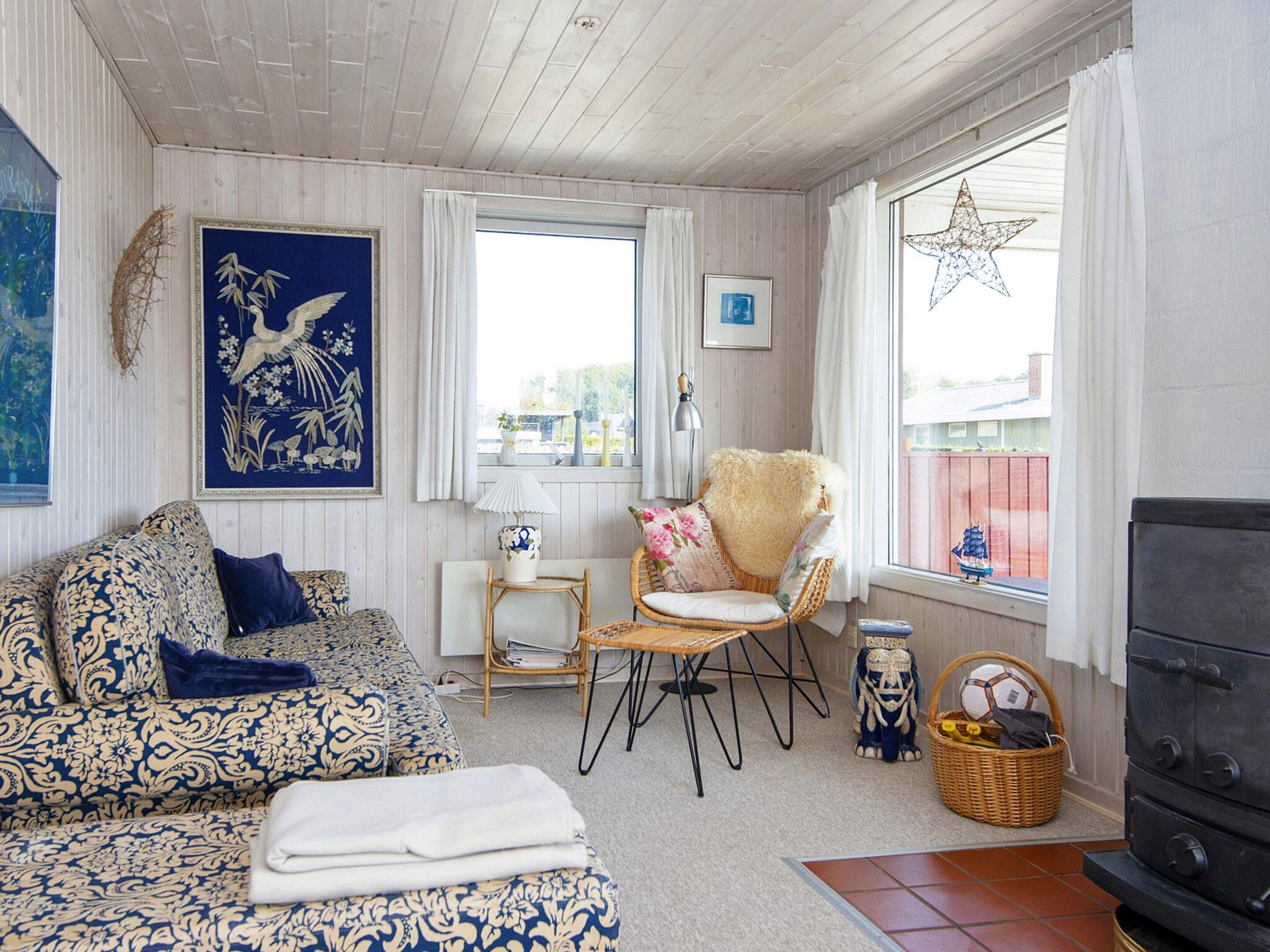 A cozy living room with a patterned sofa, a chair, a small table, and a decorative star hanging by the window.