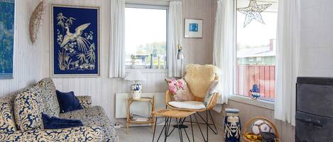 A cozy living room with a patterned sofa, a chair, a small table, and a decorative star hanging by the window.
