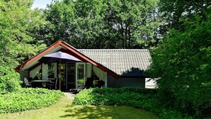 A small, single-story building with a sloped roof and a covered patio area. - 4 Person Holiday Home in Oksbol (Oksbol)