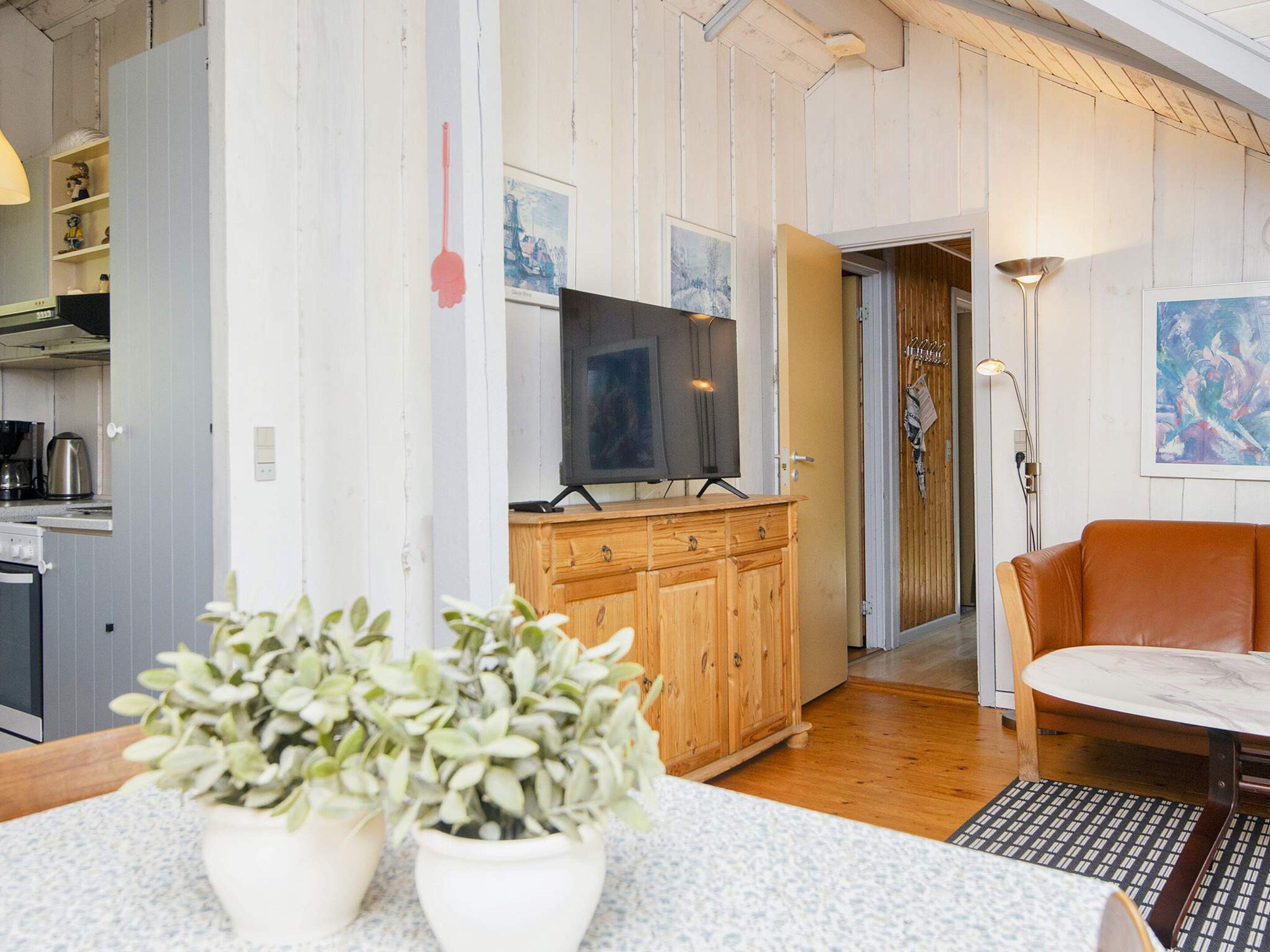 A living room with a television, wooden cabinets, a sofa, and a coffee machine.