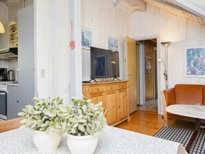 A living room with a television, wooden cabinets, a sofa, and a coffee machine.