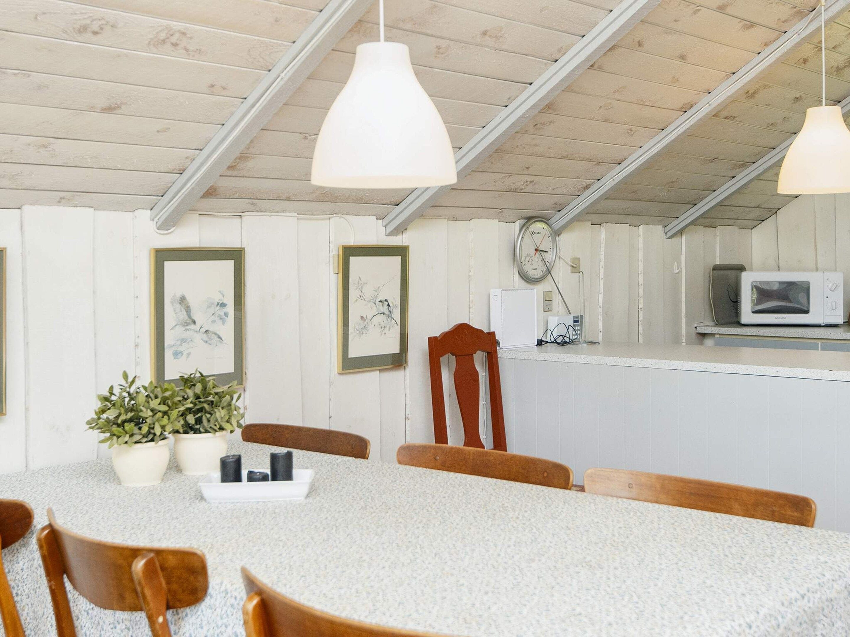 En matplats med ett runt bord, stolar, en krukväxt och en väggklocka.
