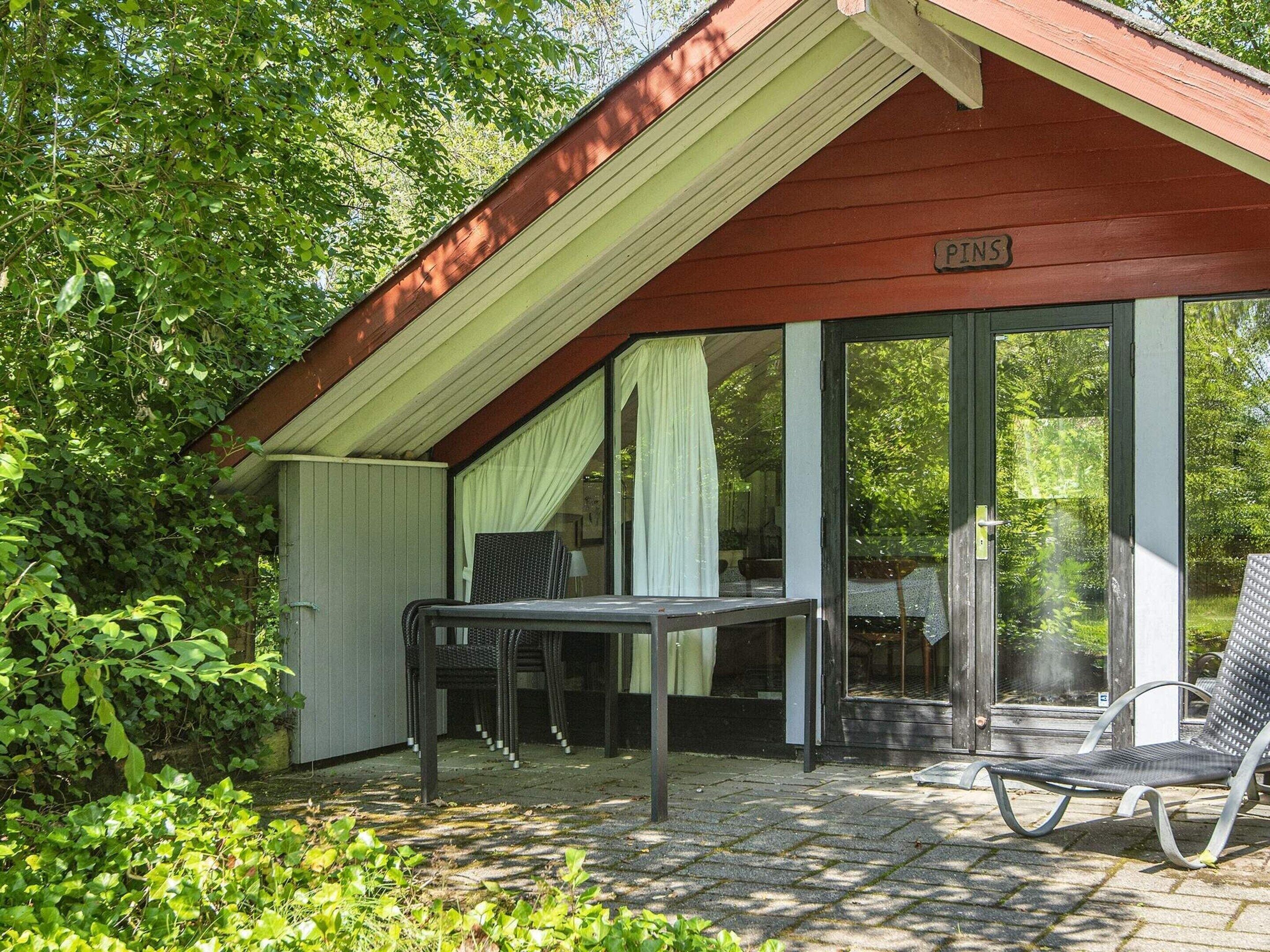 A covered outdoor seating area with a table and chairs, a glass door leading inside, and a sign reading "PINS".