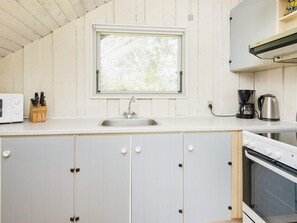 A kitchen with a window, a sink, a coffee maker, and a stove. - 4 Person Holiday Home in Oksbol (Oksbol)